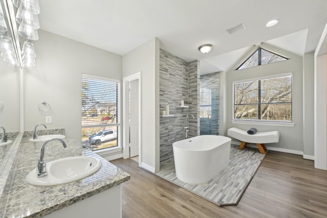 full bath with wood finished floors, a soaking tub, a sink, and double vanity