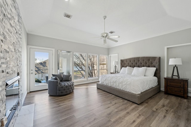 bedroom with access to outside, a raised ceiling, visible vents, and wood finished floors