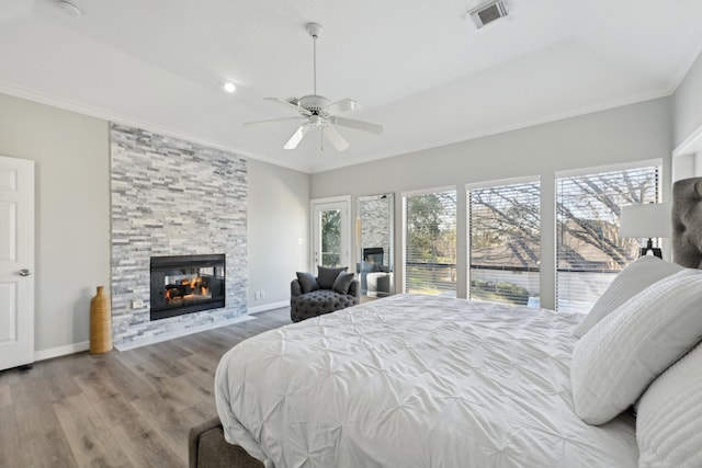 bedroom featuring a fireplace, wood finished floors, visible vents, baseboards, and ornamental molding