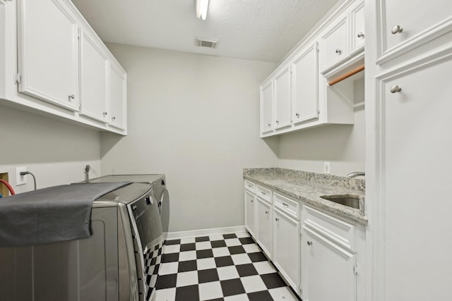 laundry room with cabinet space, visible vents, dark floors, washing machine and dryer, and a sink