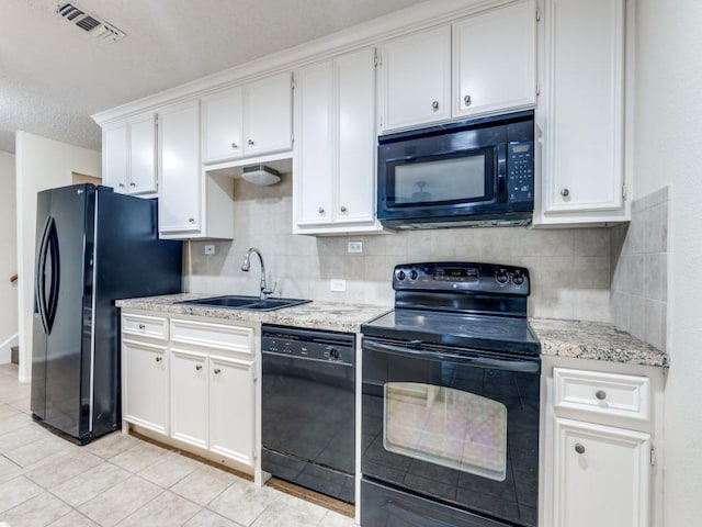 kitchen with light tile patterned floors, tasteful backsplash, white cabinets, a sink, and black appliances