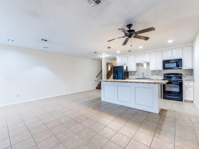 kitchen with a sink, black appliances, light countertops, and white cabinets