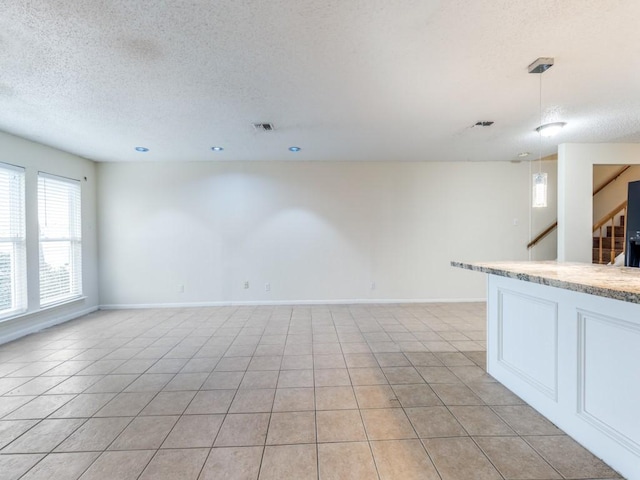 interior space featuring light tile patterned floors, stairway, a textured ceiling, and baseboards