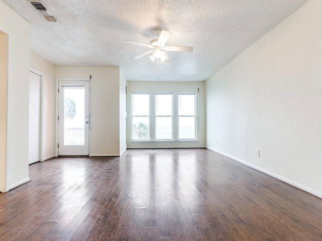 unfurnished room with visible vents, dark wood finished floors, baseboards, and ceiling fan