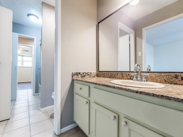 bathroom featuring toilet, a ceiling fan, vanity, baseboards, and tile patterned floors