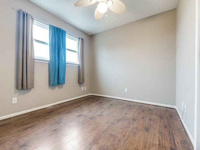 empty room with dark wood-type flooring, baseboards, and a ceiling fan