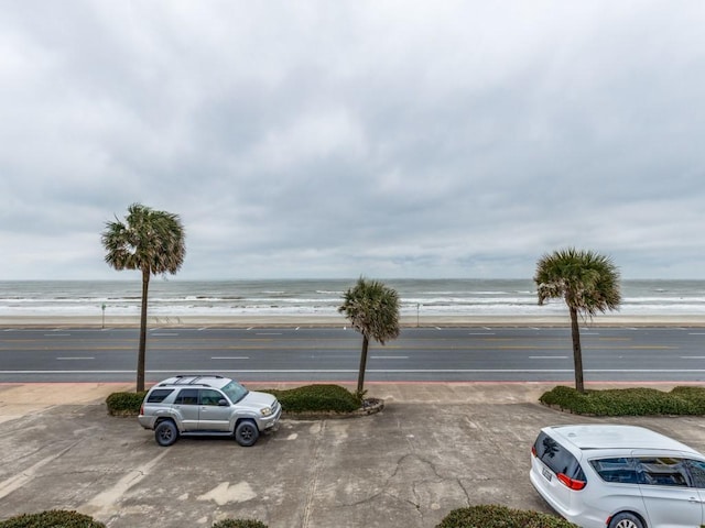 uncovered parking lot featuring a water view and a view of the beach