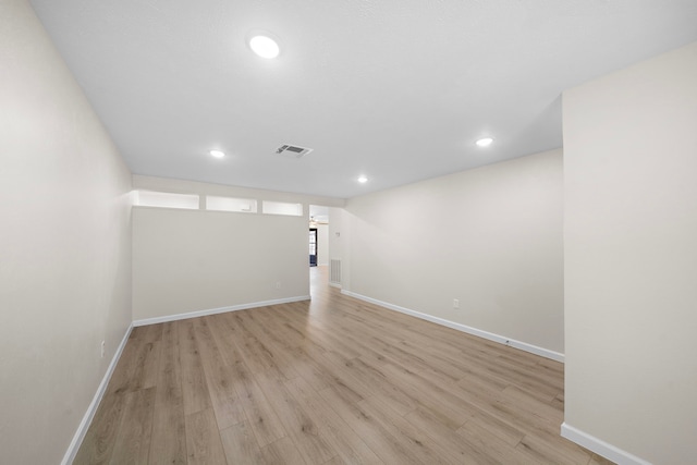 empty room with baseboards, visible vents, and light wood finished floors