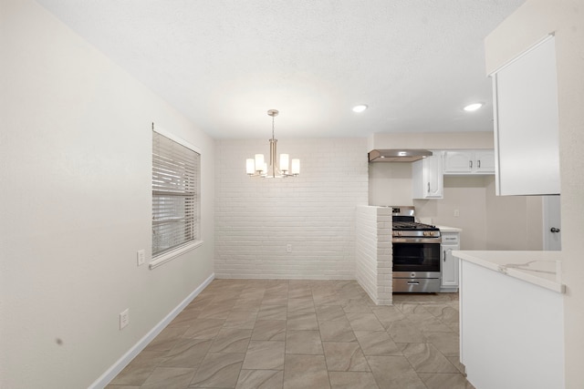 kitchen with white cabinets, gas range, light stone counters, hanging light fixtures, and an inviting chandelier