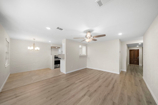 unfurnished living room featuring brick wall, visible vents, light wood-style flooring, and ceiling fan with notable chandelier