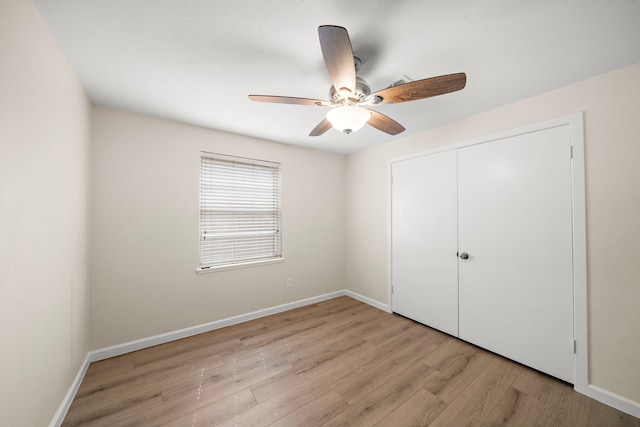 unfurnished bedroom featuring light wood-style floors, ceiling fan, baseboards, and a closet