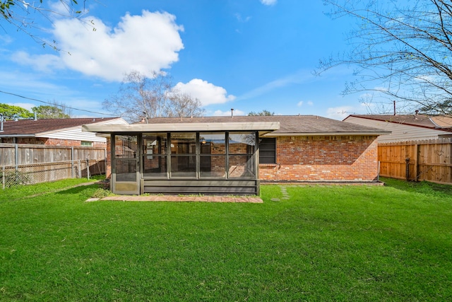 back of property with a sunroom, a fenced backyard, a lawn, and brick siding