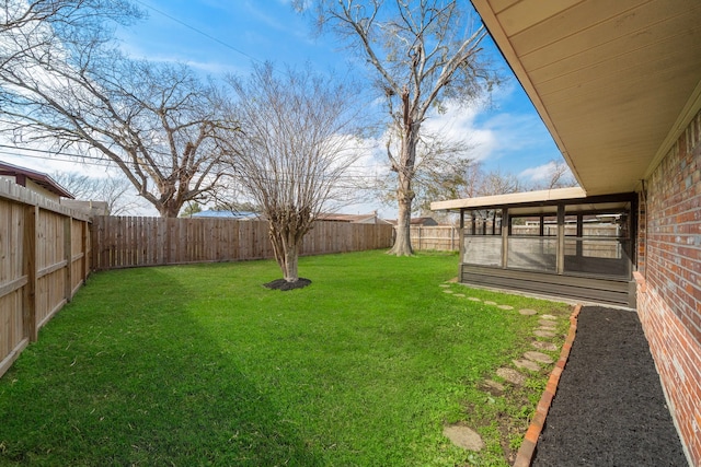 view of yard featuring a sunroom and a fenced backyard