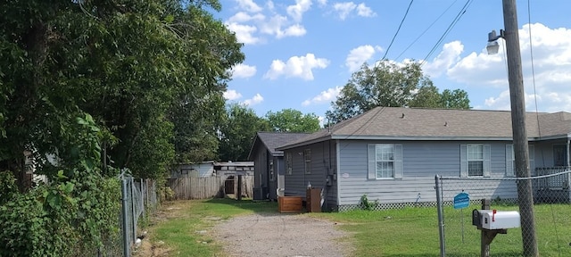 view of property exterior featuring roof with shingles, fence, and a yard