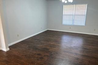 empty room with baseboards and dark wood-type flooring