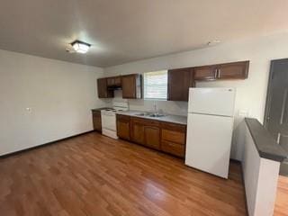 kitchen featuring a sink, white appliances, and wood finished floors