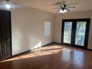 spare room featuring french doors, light wood-type flooring, a ceiling fan, and baseboards