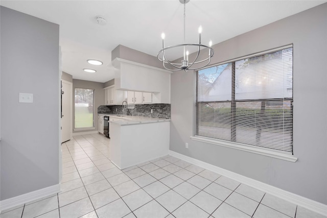 kitchen featuring a sink, white cabinetry, light countertops, decorative backsplash, and decorative light fixtures