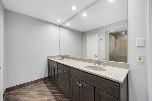 bathroom featuring a sink, a shower stall, baseboards, and double vanity