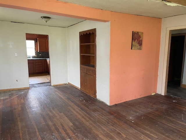 empty room featuring baseboards and dark wood-type flooring