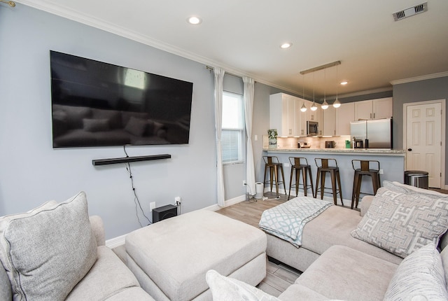 living room with ornamental molding, recessed lighting, visible vents, and baseboards