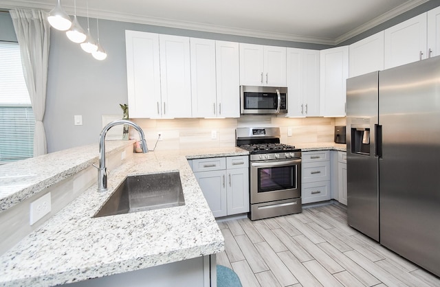 kitchen with light stone counters, appliances with stainless steel finishes, ornamental molding, backsplash, and a sink