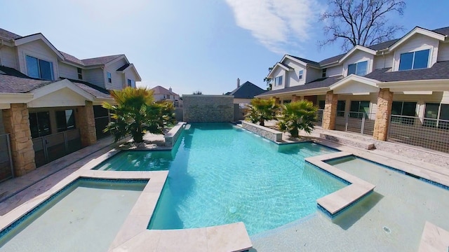 view of pool featuring a fenced in pool, a residential view, and an in ground hot tub