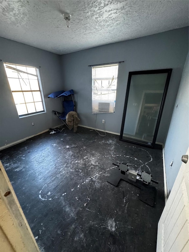 interior space with a textured ceiling and baseboards