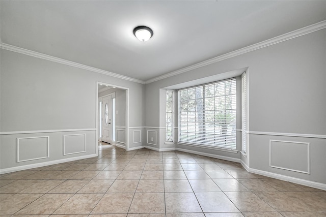 empty room with light tile patterned floors, a decorative wall, and crown molding