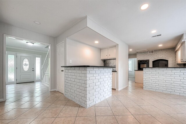 kitchen with light tile patterned floors, dark countertops, white cabinetry, oven, and a peninsula