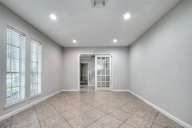 spare room featuring light tile patterned floors, baseboards, stairs, and visible vents