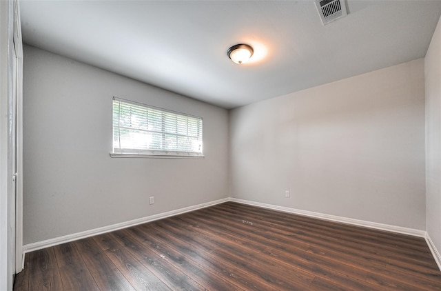 spare room featuring dark wood-style floors, visible vents, and baseboards