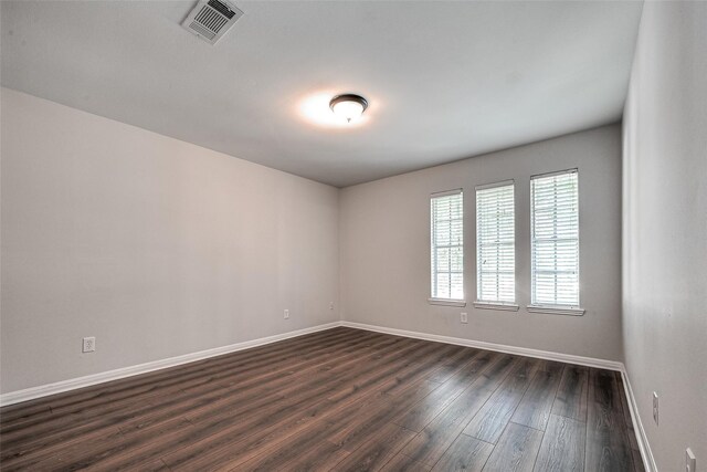 unfurnished room with dark wood finished floors, visible vents, and baseboards