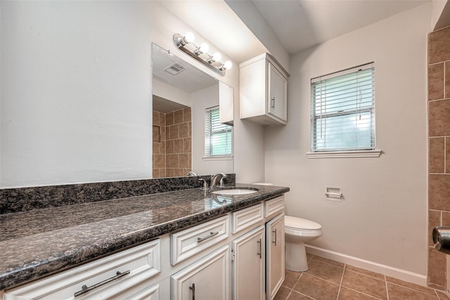 bathroom with toilet, vanity, baseboards, visible vents, and tile patterned floors