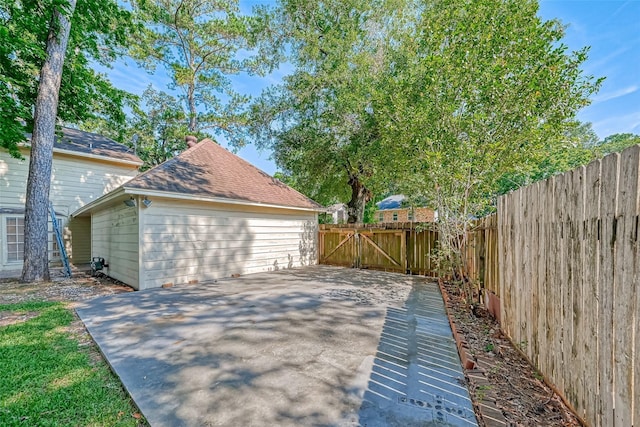 view of property exterior with a patio, a fenced backyard, and a gate