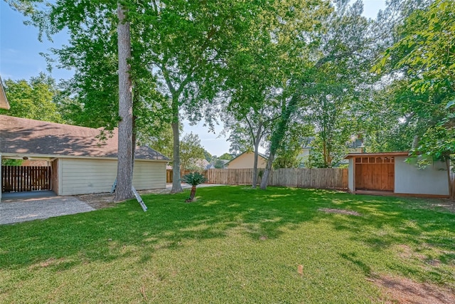 view of yard featuring an attached garage, fence, and an outdoor structure