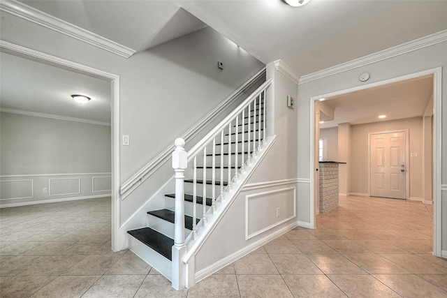 stairway featuring ornamental molding, tile patterned flooring, and wainscoting