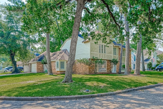 view of front of home with an attached garage, a front yard, and brick siding