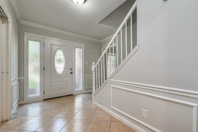 entrance foyer featuring a wainscoted wall, a decorative wall, stairway, ornamental molding, and light tile patterned flooring