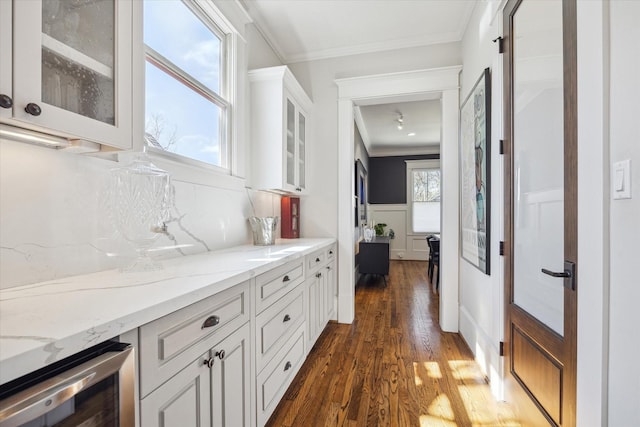 interior space with ornamental molding, wine cooler, a wealth of natural light, and dark wood finished floors