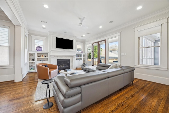 living room featuring visible vents, wood finished floors, crown molding, and a glass covered fireplace