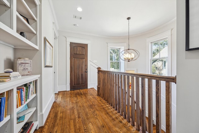 hall featuring baseboards, visible vents, dark wood-style flooring, crown molding, and a chandelier