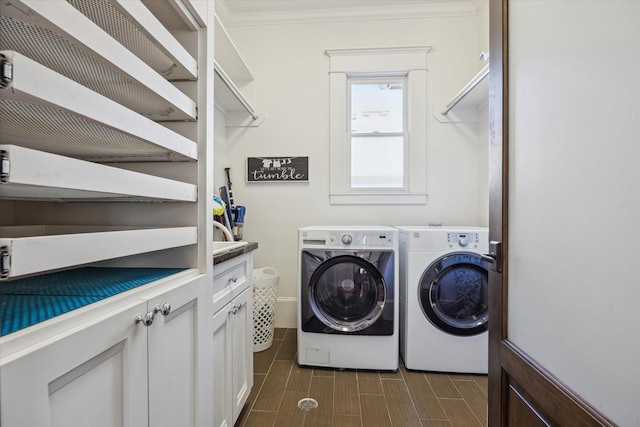 laundry area featuring ornamental molding, wood tiled floor, cabinet space, and washing machine and clothes dryer