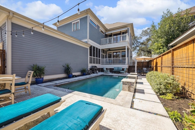 view of swimming pool with a sunroom, a fenced backyard, a fenced in pool, and a patio