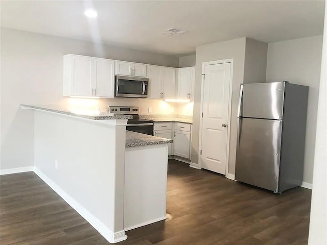 kitchen with stainless steel appliances, white cabinets, a peninsula, and dark wood-type flooring