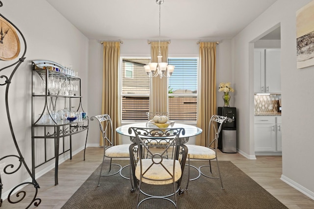 dining area with baseboards, light wood-style flooring, and a notable chandelier