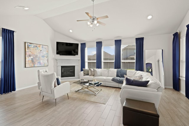 living room with a wealth of natural light, a glass covered fireplace, vaulted ceiling, and light wood-style flooring