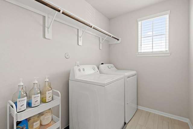 clothes washing area with laundry area, baseboards, and separate washer and dryer