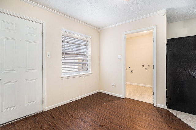 foyer entrance featuring a textured ceiling, ornamental molding, wood finished floors, and baseboards