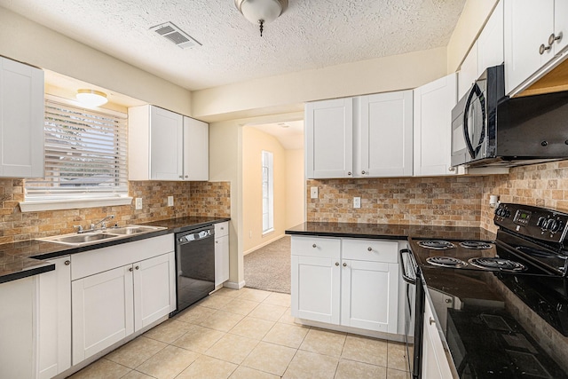 kitchen with dark countertops, black appliances, white cabinets, and a sink